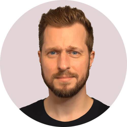 Professional headshot: smiling man with beard, friendly expression